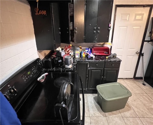 3751 Wilson Dr, Corpus Christi, TX 78408 - kitchen featuring light tile patterned floors, black range with gas stovetop, dark countertops, and concrete block wall