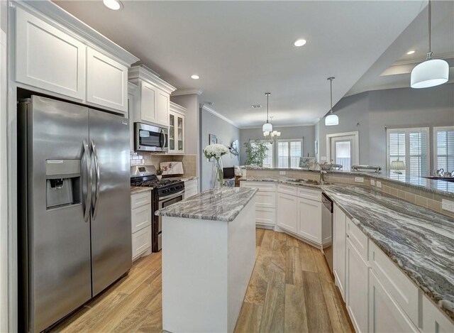 kitchen featuring white cabinetry, decorative light fixtures, stainless steel appliances, and a center island