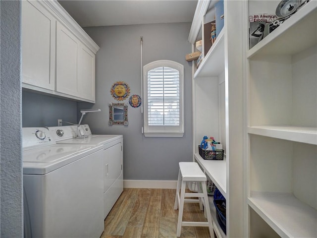 laundry area with washer and clothes dryer, light hardwood / wood-style floors, and cabinets