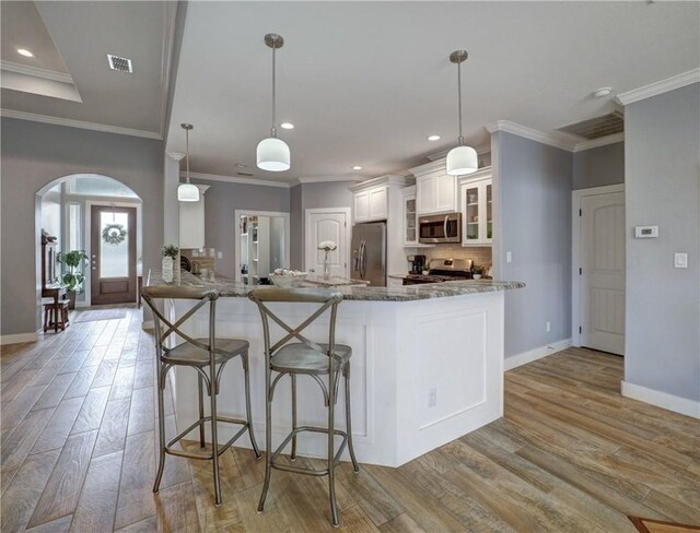 kitchen featuring hanging light fixtures, appliances with stainless steel finishes, stone countertops, and white cabinets