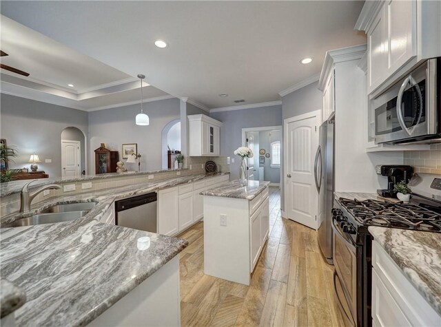 kitchen featuring sink, white cabinetry, light stone counters, a center island, and appliances with stainless steel finishes