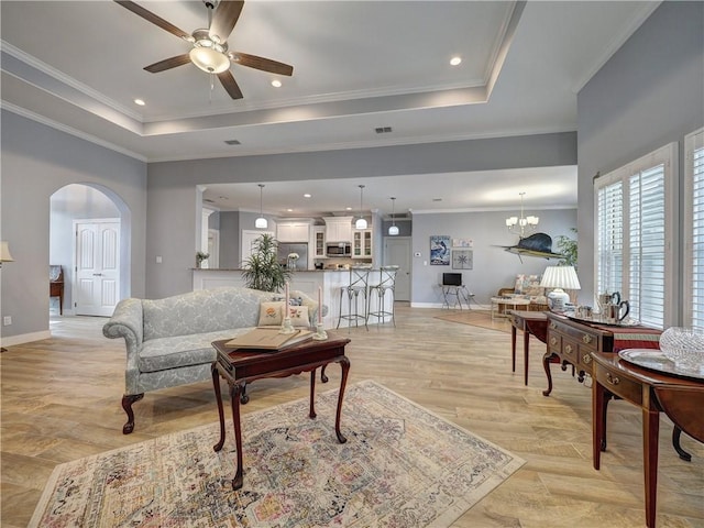 living room featuring a raised ceiling, ornamental molding, and light wood-type flooring