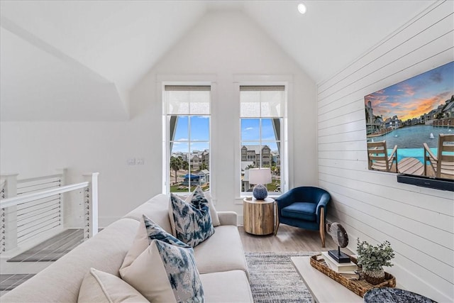 living area with vaulted ceiling, wood finished floors, and wooden walls