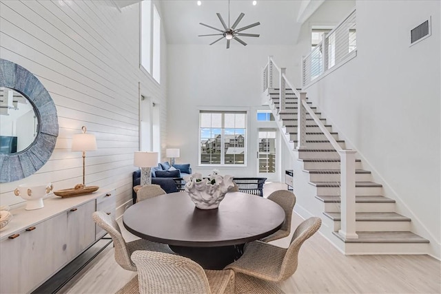 dining room featuring stairway, light wood-style flooring, visible vents, and a wealth of natural light