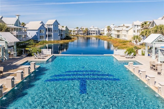 community pool with a residential view, a patio area, fence, and a water view