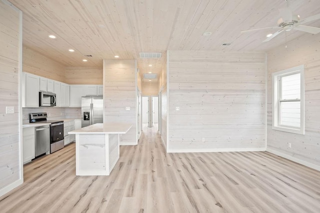 kitchen featuring wooden ceiling, stainless steel appliances, wood walls, a kitchen island, and light wood-type flooring