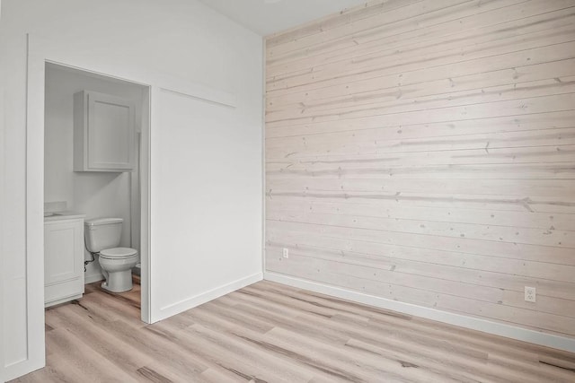 interior space featuring hardwood / wood-style flooring, wood walls, and toilet