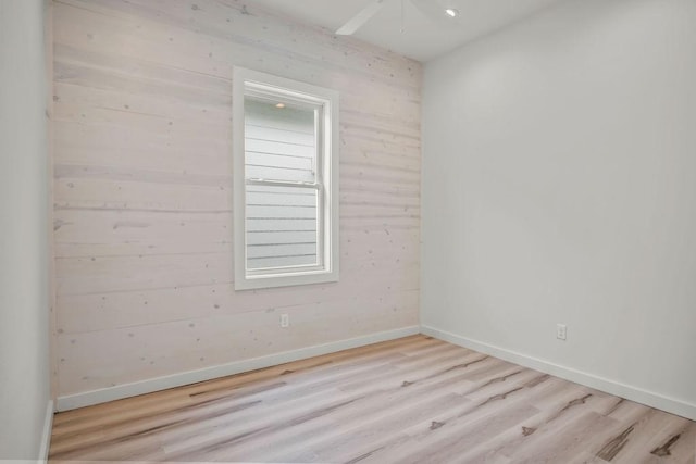 empty room featuring light hardwood / wood-style floors and wooden walls