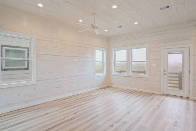 empty room featuring ceiling fan, wooden walls, wooden ceiling, and light wood-type flooring