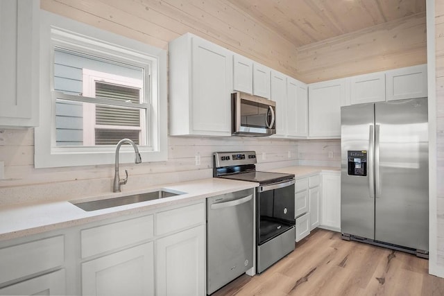 kitchen featuring white cabinets, sink, appliances with stainless steel finishes, light hardwood / wood-style floors, and wood ceiling