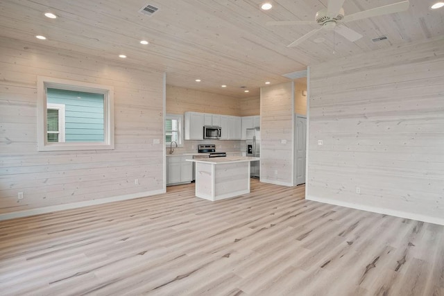 kitchen featuring wooden walls, a kitchen island, wooden ceiling, and appliances with stainless steel finishes