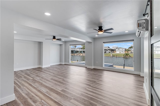 empty room featuring plenty of natural light, a water view, light hardwood / wood-style floors, and ceiling fan