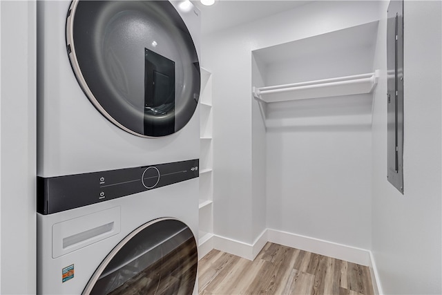 laundry room featuring stacked washing maching and dryer and light wood-type flooring