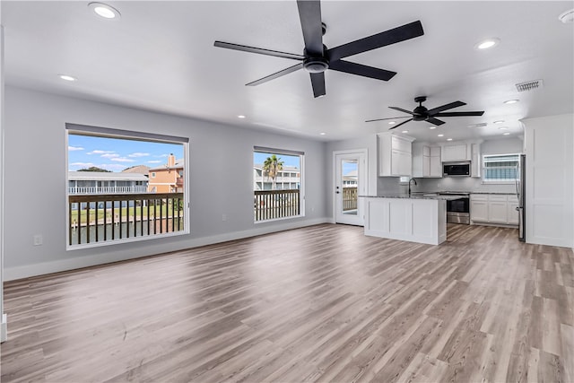 unfurnished living room with a wealth of natural light, sink, and light wood-type flooring