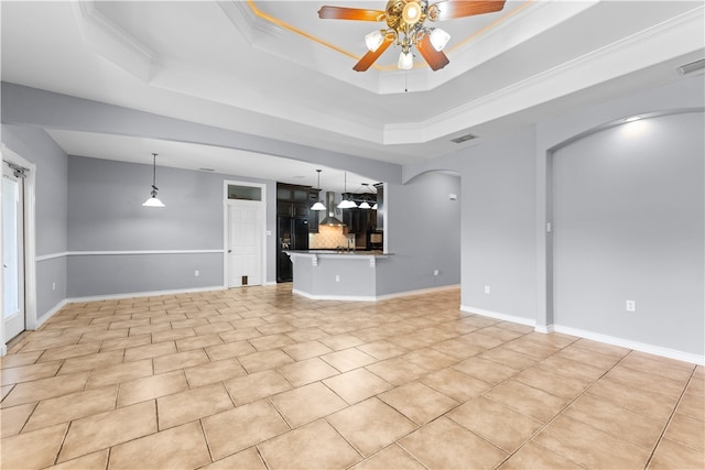 unfurnished living room featuring ceiling fan, a raised ceiling, and ornamental molding