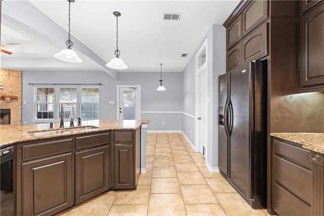 kitchen featuring black appliances, light stone counters, dark brown cabinets, and a fireplace