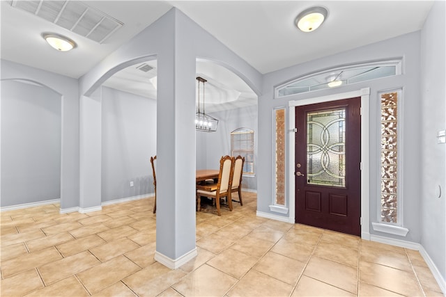 tiled foyer entrance with a chandelier