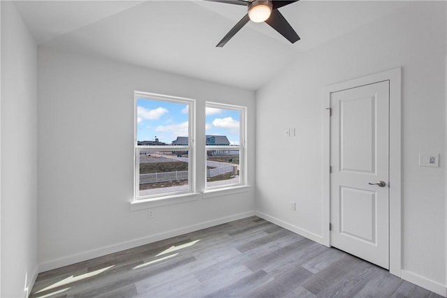 empty room featuring vaulted ceiling, light hardwood / wood-style floors, and ceiling fan