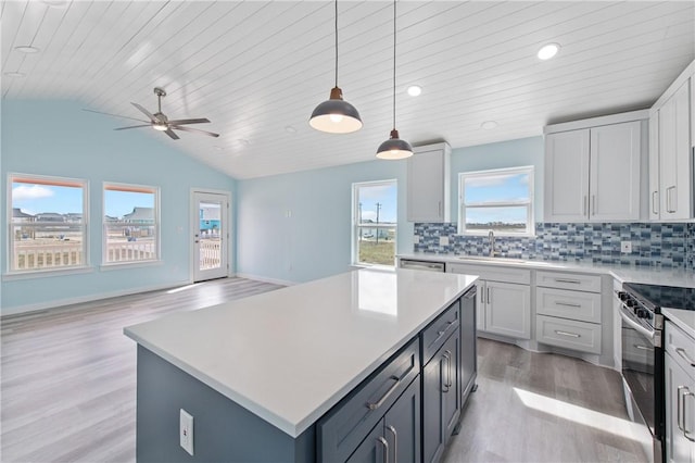 kitchen with lofted ceiling, electric range, a center island, decorative backsplash, and decorative light fixtures