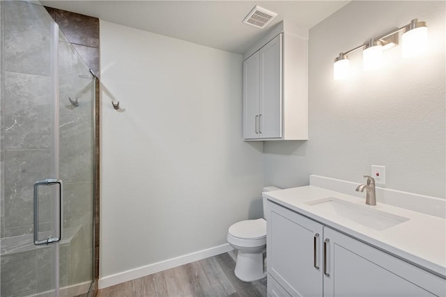 bathroom featuring wood-type flooring, toilet, an enclosed shower, and vanity