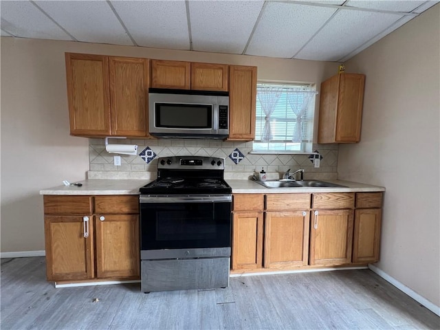 kitchen featuring appliances with stainless steel finishes, sink, tasteful backsplash, and light wood-type flooring