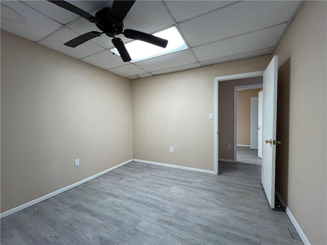 spare room with ceiling fan, a drop ceiling, and wood-type flooring