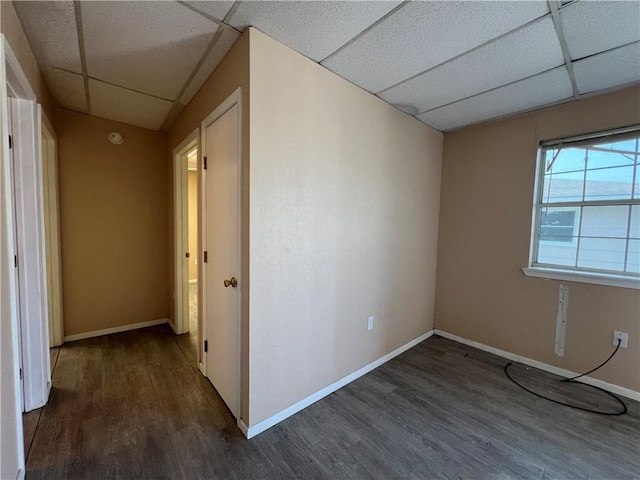 unfurnished room featuring a paneled ceiling and dark hardwood / wood-style flooring