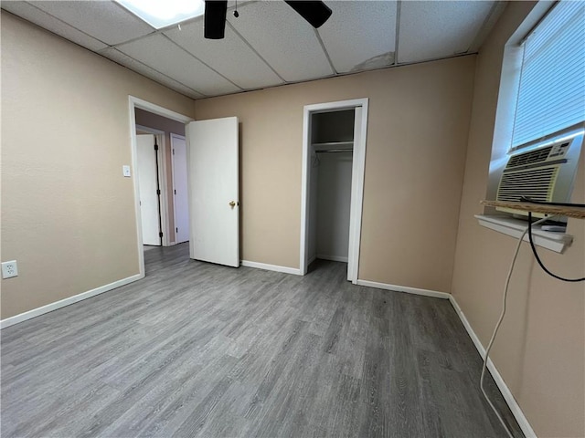 unfurnished bedroom featuring cooling unit, a closet, ceiling fan, hardwood / wood-style floors, and a drop ceiling