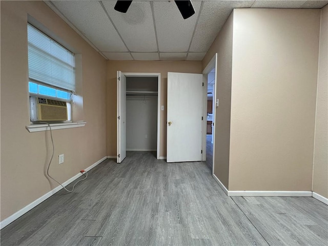 unfurnished bedroom with a paneled ceiling, a closet, light wood-type flooring, and ceiling fan