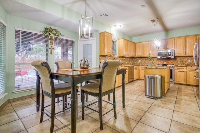 kitchen with appliances with stainless steel finishes, decorative backsplash, visible vents, and a center island