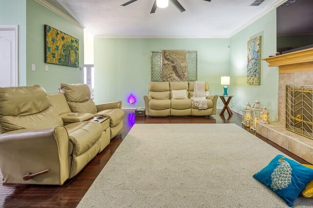 living room with visible vents, a premium fireplace, dark wood-type flooring, ornamental molding, and ceiling fan