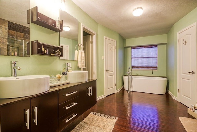 bathroom featuring a soaking tub, wood finished floors, a sink, and double vanity