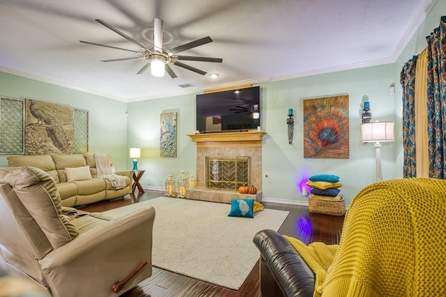 living room featuring baseboards, a tile fireplace, wood finished floors, and crown molding