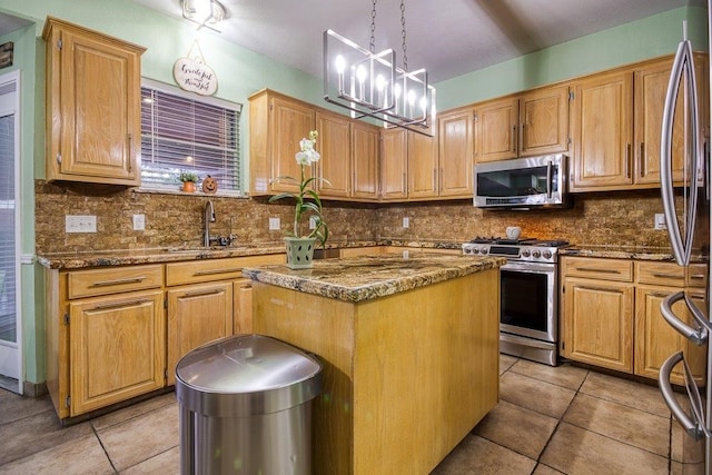 kitchen featuring tasteful backsplash, a kitchen island, appliances with stainless steel finishes, dark stone countertops, and a sink