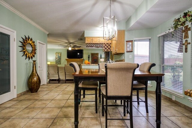 dining area featuring light tile patterned floors, ceiling fan with notable chandelier, baseboards, and crown molding