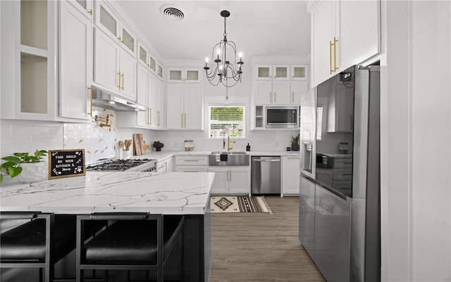 514 W 4th St, Sinton, TX 78387 - kitchen with stainless steel appliances, a sink, under cabinet range hood, a peninsula, and a chandelier
