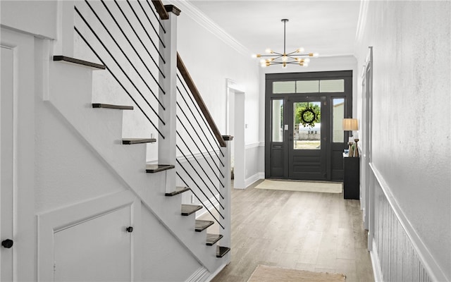 foyer entrance with light hardwood / wood-style floors, crown molding, and a notable chandelier