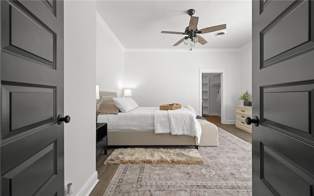 bedroom featuring a spacious closet, ceiling fan, dark hardwood / wood-style flooring, a closet, and ornamental molding