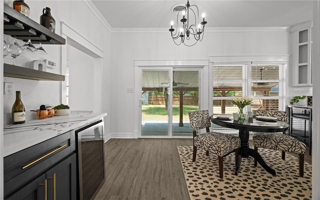 dining area with ornamental molding, dark wood-type flooring, wine cooler, and an inviting chandelier