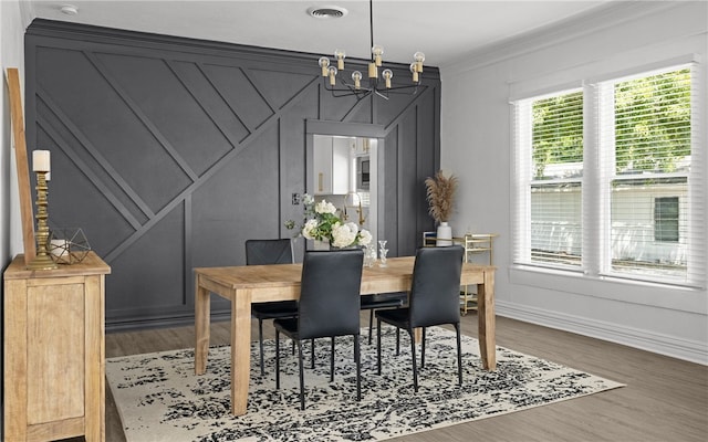 dining space featuring a notable chandelier, wood-type flooring, and crown molding