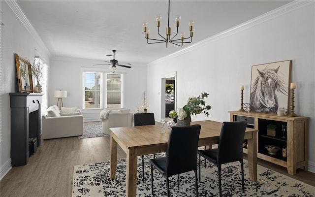 dining room with ornamental molding, ceiling fan with notable chandelier, and hardwood / wood-style flooring