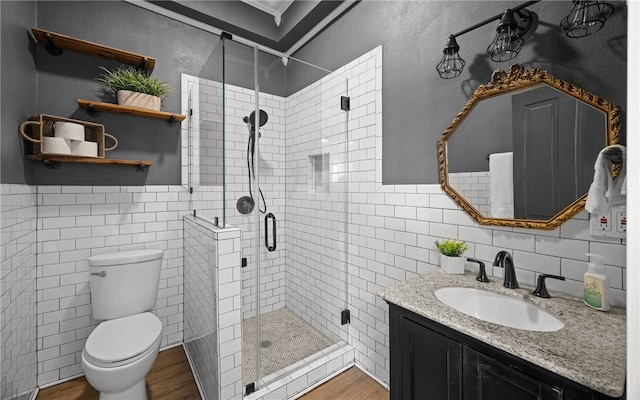 bathroom featuring hardwood / wood-style floors, vanity, toilet, tile walls, and walk in shower