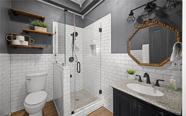 514 W 4th St, Sinton, TX 78387 - bathroom with tile walls, wood finished floors, a shower stall, toilet, and vanity
