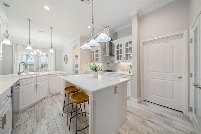 kitchen with arched walkways, a sink, backsplash, a center island, and glass insert cabinets