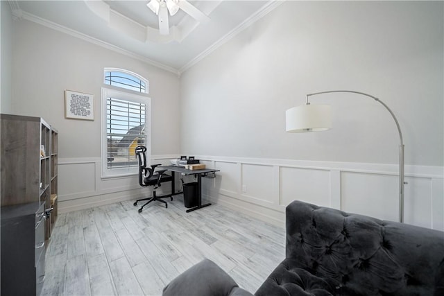 office space featuring a raised ceiling, wainscoting, crown molding, light wood-type flooring, and a decorative wall