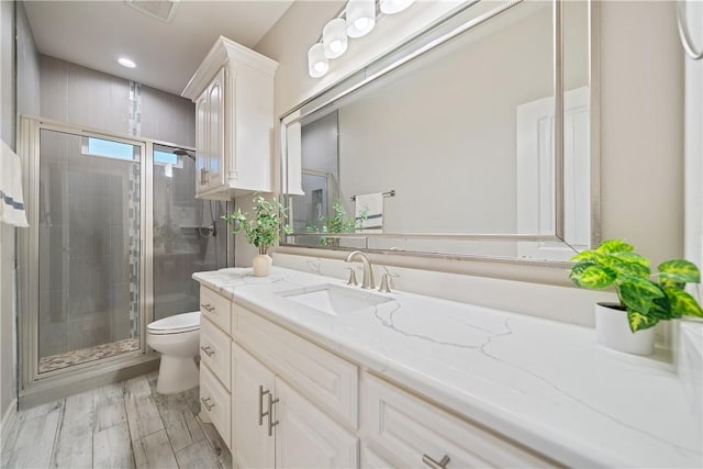 full bath with wood finished floors, a shower stall, toilet, and vanity