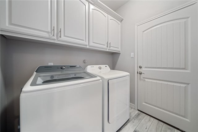 washroom featuring light wood-type flooring, cabinet space, and washer and dryer