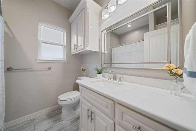 full bath with toilet, wood finished floors, vanity, and baseboards