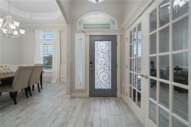 entryway featuring a tray ceiling, baseboards, an inviting chandelier, and wood finished floors