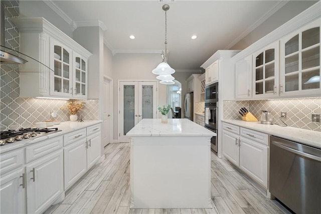 kitchen with crown molding, stainless steel appliances, wood tiled floor, white cabinetry, and a kitchen island